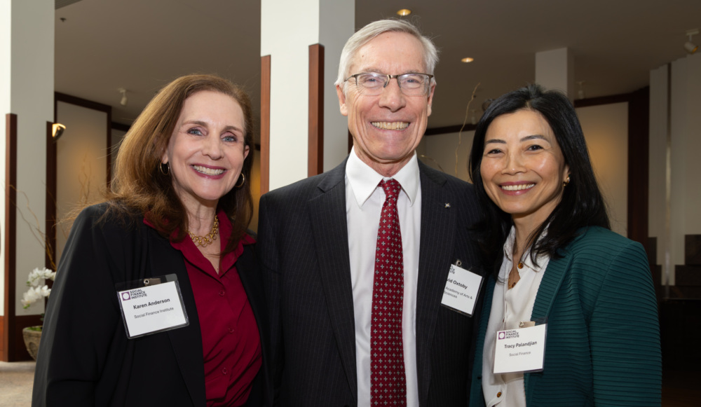 Karen Anderson, David Oxtoby, and Tracy Palandjian smile, standing indoors at a formal event.
